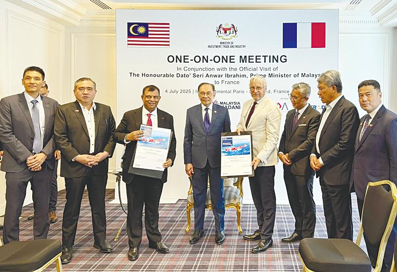 Anwar (fourth, left) looks on as Fernandes (third, left) and Scherer (fourth, right) display the signed documents in Paris on Friday.