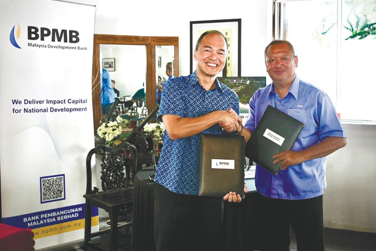 Wee (left) and Lau exchange documents after signing the Lundu Beach Resort financing agreement.
