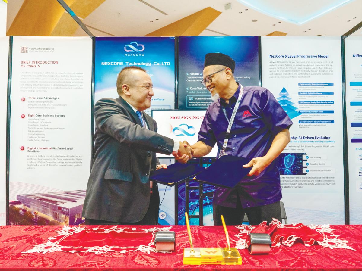 Nexcore Technology CEO Tang Yang (left) and Abdul Wahab exchanging documents after the signing ceremony.