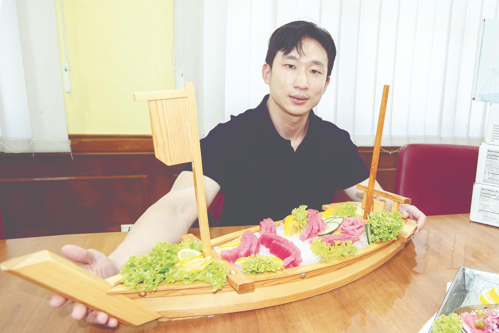 Lee presenting Labuan Food Industries’ premium sashimi-grade tuna product during an interview at the company’s office. – Bernamapic