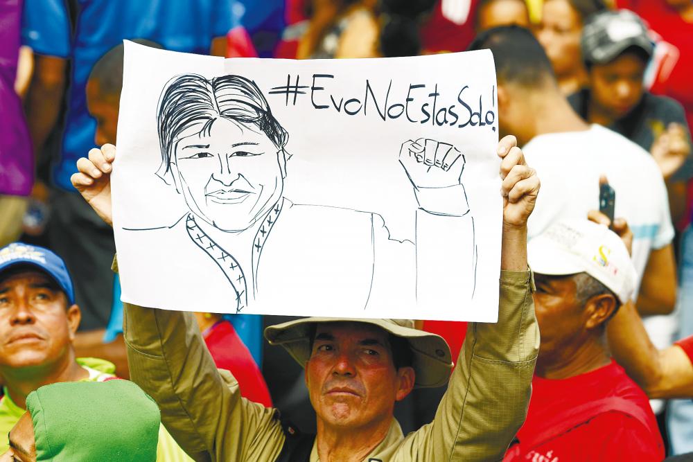 A member of the Bolivarian National Guard holds a sign depicting Morales reading “You are not alone” during a pro-government demonstration in Caracas on Saturday. – AFPpix