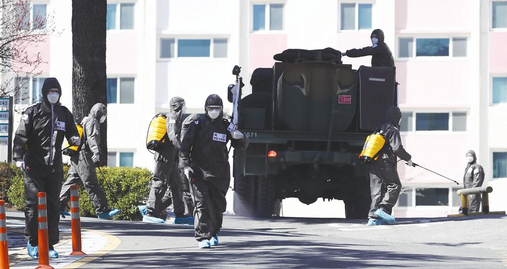 South Korean soldiers spray disinfectant at an apartment complex after 46 residents were confirmed to have the coronavirus in Daegu on Wednesday. – AFPpix/Yonhap