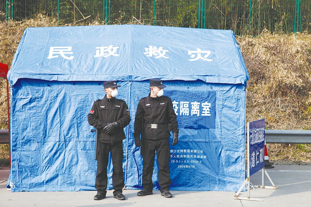 Security personnel stand in front of a disaster relief tent at a checkpoint in Yunxi county, Hunan province, near the border to Hubei province. – Reuterspix