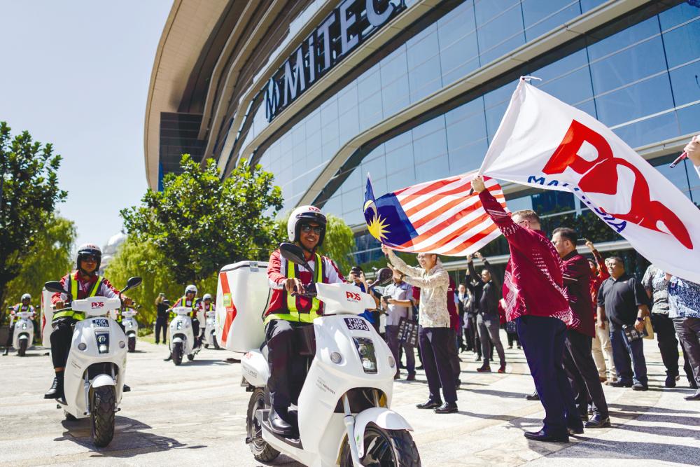 Fahmi (with Malaysia flag) and Brewer (with Pos Malaysia flag) flagging off 10 ES11 X2 Eclimo EV-Bikes at the launch yesterday.