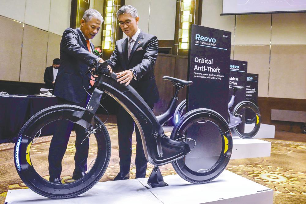 Artroniq chairman Datuk Seri Abdul Rahim Jaafar (left) briefing Tengku Zafrul on the features of the e-bicycle. – ADIB RAWI/THE SUN