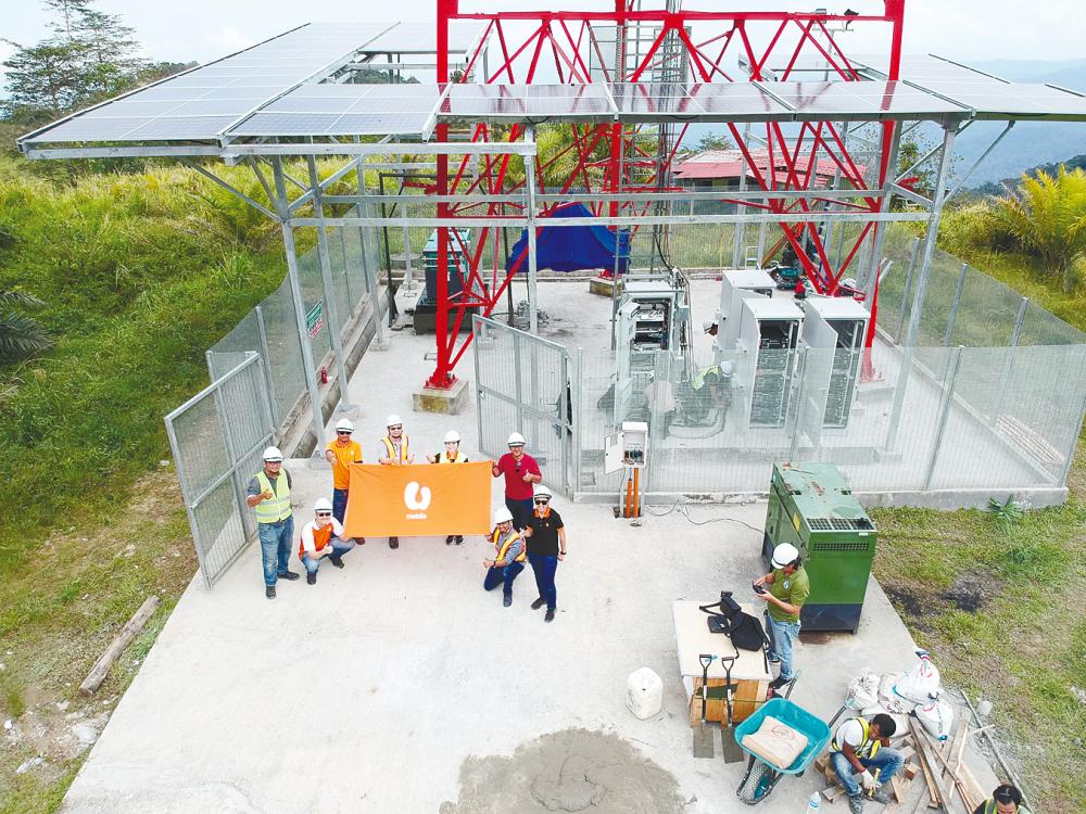 The U Mobile team setting up a solar hybrid-powered cell site at its telecommunication tower in Kimanis, Sabah.