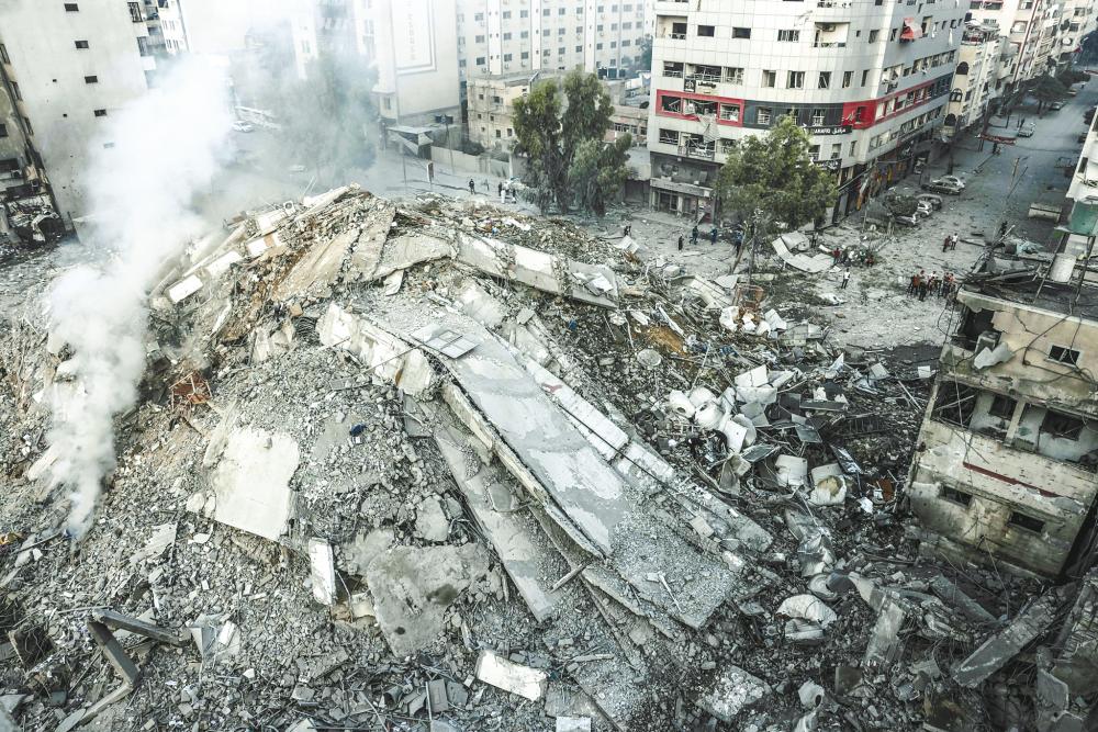 Residents assessing the ruins of a building destroyed by Israeli airstrikes in Gaza City yesterday. – AFPPIC