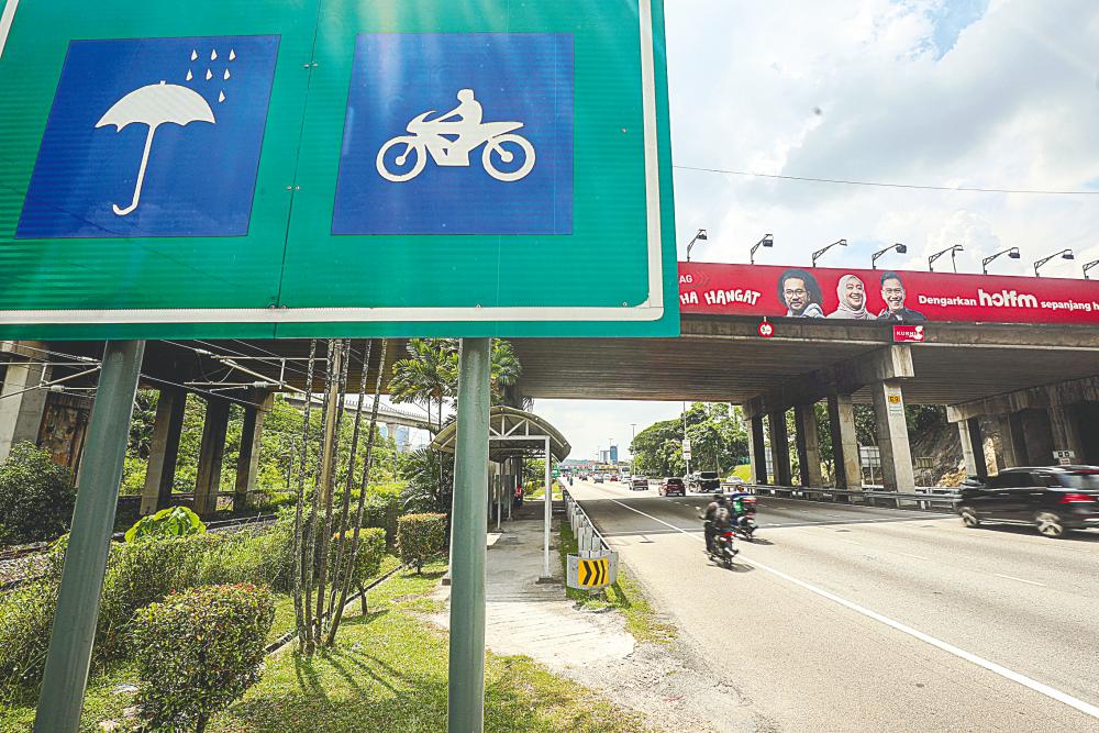 A rain shelter set up under a flyover, with metal railings to protect motorcyclists from traffic. – AMIRUL SYAFIQ/THESUN