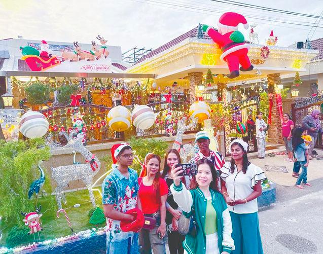 Visitors pose with house owner Charles Dorney (wearing cap), his wife Christe Samasundram (right) and son Dohnaven. – MASRY CHE ANI/THESUN