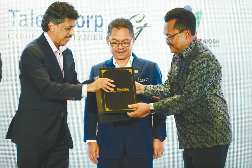 Mathew presenting a memento to National Institute for Occupational Safety and Health executive director Ayop Salleh, witnessed by Human Resources Deputy Minister Datuk Mustapha Sakmud, during the launch of the Future Skills Talent Council initiative. – Amirul Syafiq/theSun