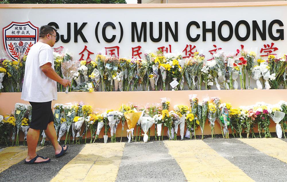 A resident joins others in placing flowers outside Sekolah Jenis Kebangsaan Cina (C) Mun Choong in Kuala Lumpur in an outpouring of condolences. Twenty teachers from the school were among those affected by the landslide. – BERNAMAPIC