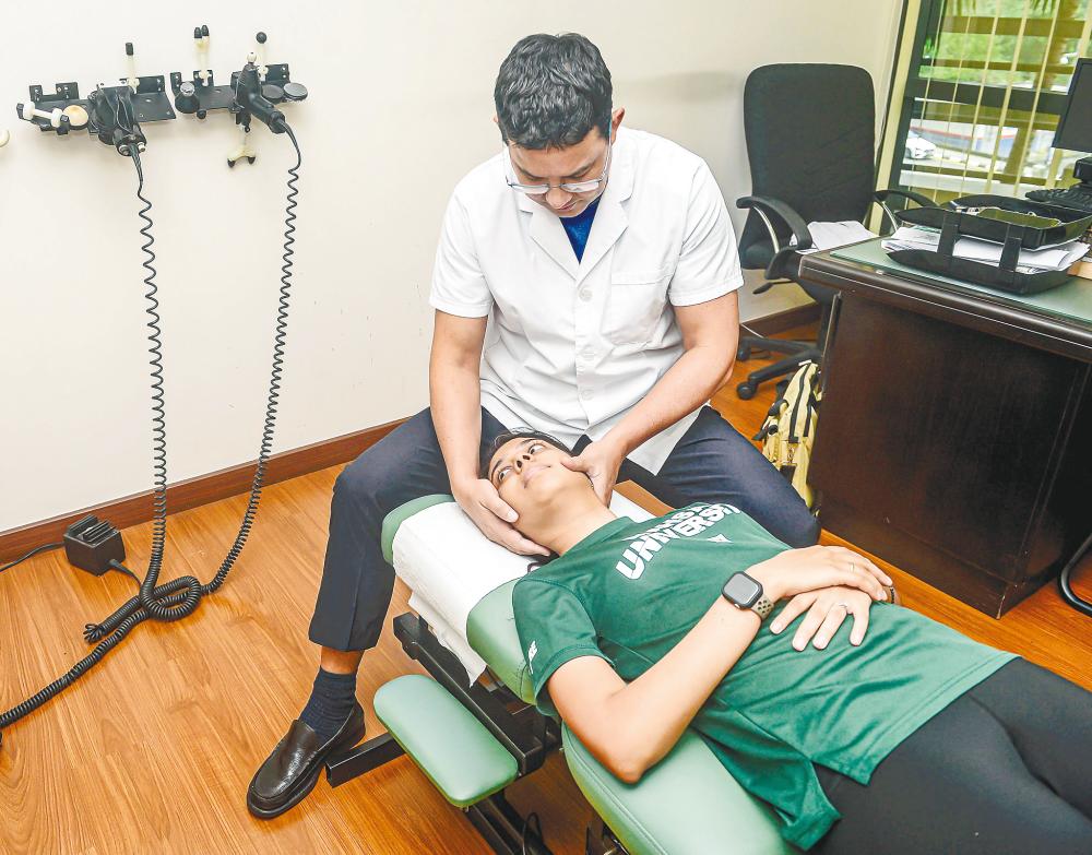 Abader treating a patient at his clinic. – ADIB RAWI YAHYA/THESUN