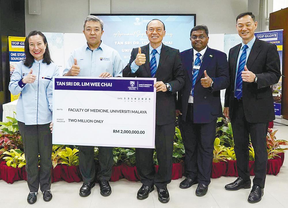 Lim (centre) making the contribution to UM at the event. – AMIRUL SYAFIQ/THESUN