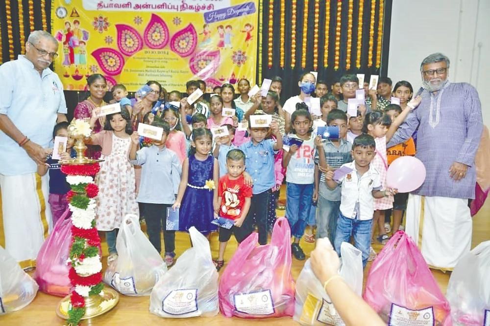 Murugiah (left) and PHA committee member K. Ganesan (right) with children and parents during the event. – Pix courtesy of Penang Hindu Association