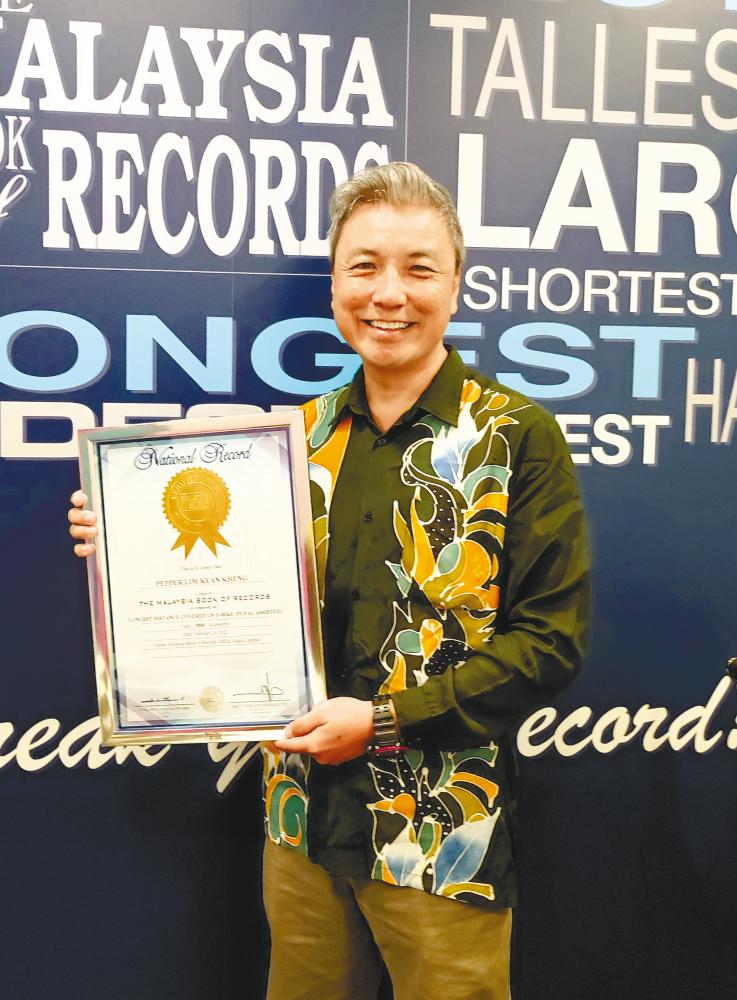 Lim with the Malaysia Book of Records certificate he received at the end of his cycling-for-charity project.