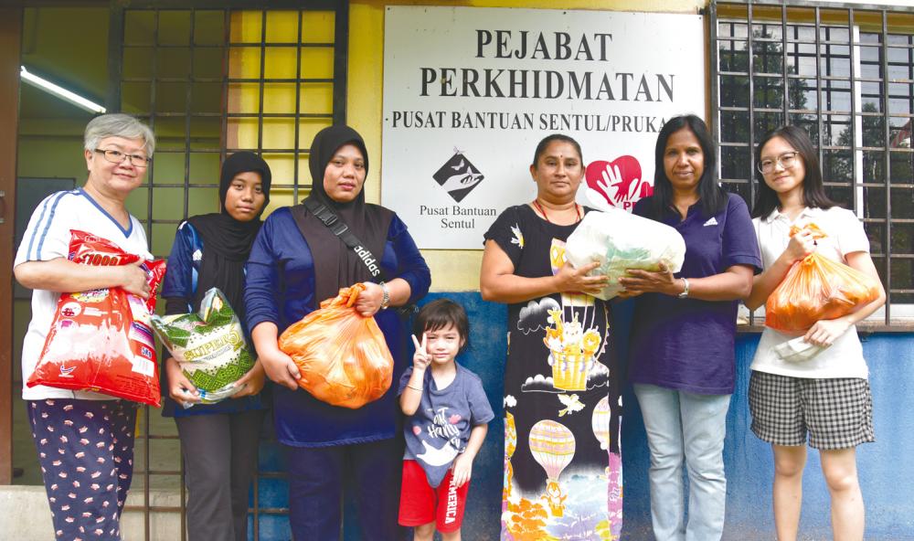 Arulanthu (second from right) handing out aid items to residents. – SYAZWAN KAMAL/THESUN