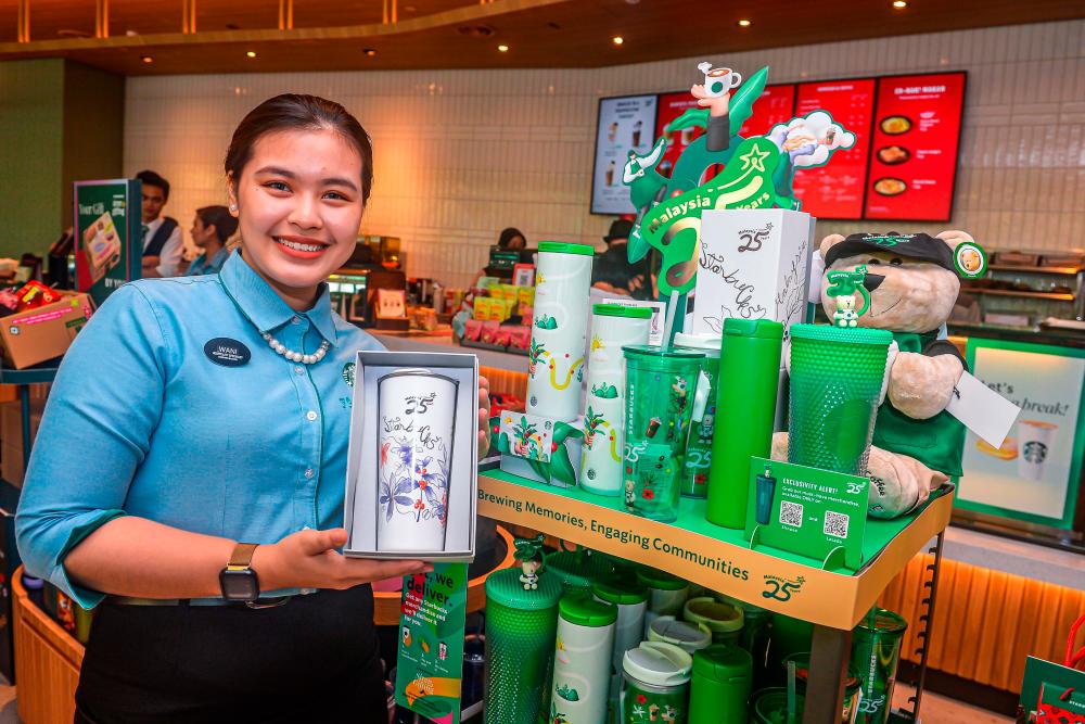 A Starbucks employee with exclusive 25th anniversary merchandise. - THESUNPIX