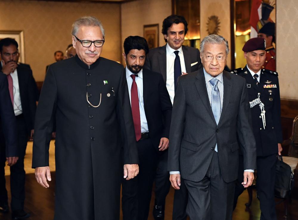 Prime Minister Tun Dr Mahathir Mohamad walks with Pakistan President Dr Arif Alivi (L) during a courtesy call at the President’s House on March 23, 2019. — Bernama