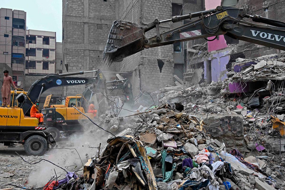 Rescue workers conduct a search operation amid the debris of a collapsed residential building in Karachi on July 5, 2025. Rescue teams pulled more bodies from the rubble of a five-storey building collapse in Pakistan overnight, taking the toll on July 5 to 14 as the recovery operation continued for a second day. - Rizwan TABASSUM / AFP