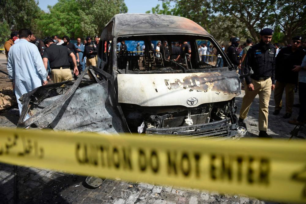 Police inspect a site around damaged vehicles following a suicide bombing near the Confucious Institute affiliated with the Karachi University, in Karachi on April 26, 2022. AFPpix