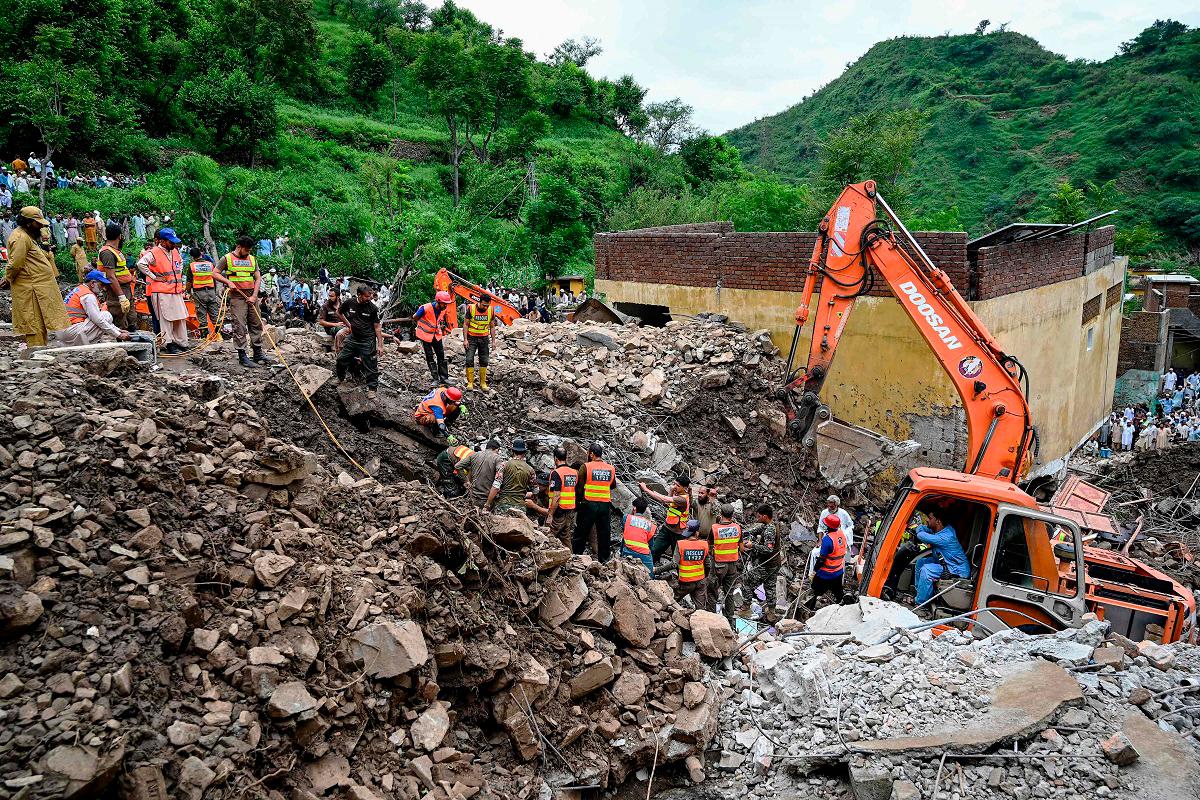 Relief personnel use excavators to clear rubble of collapsed houses as they search through the debris for victims during a rescue operation, a day after a cloudburst at the Dalori village in Swabi district, in Pakistan’s mountainous Khyber Pakhtunkhwa province on August 19, 2025. - Aamir QURESHI / AFP