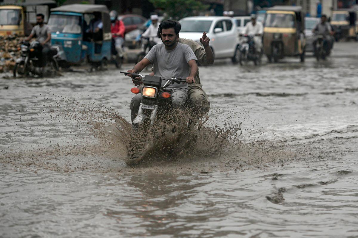 Commuters make their way through a flooded street after heavy rainfall in Karachi on June 28, 2025. - Rizwan TABASSUM / AFP