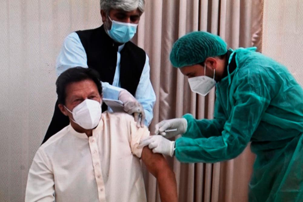 This image grab taken from a handout video released on March 18, 2021 by the Pakistan Prime Minister Office shows Pakistan’s Prime Minister Imran Khan (L) receiving a dose of the Chinese-made Sinopharm vaccine against the Covid-19 coronavirus, at the Prime Minister House in Islamabad. -AFP /Pakistan Prime Minister Office
