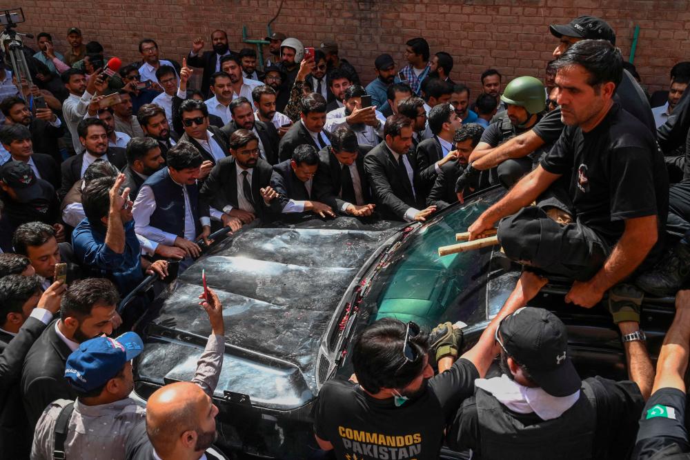 Security personnel and supporters of former prime minister Imran khan gather around his vehicle upon his arrival in High court in Lahore on May 15, 2023. AFPPIX
