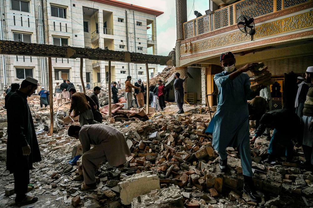 Plain-clothed policemen and labourers remove debris from a damaged mosque following January's 30 suicide blast inside the police headquarters in Peshawar on February 1, 2023. AFPPIX
