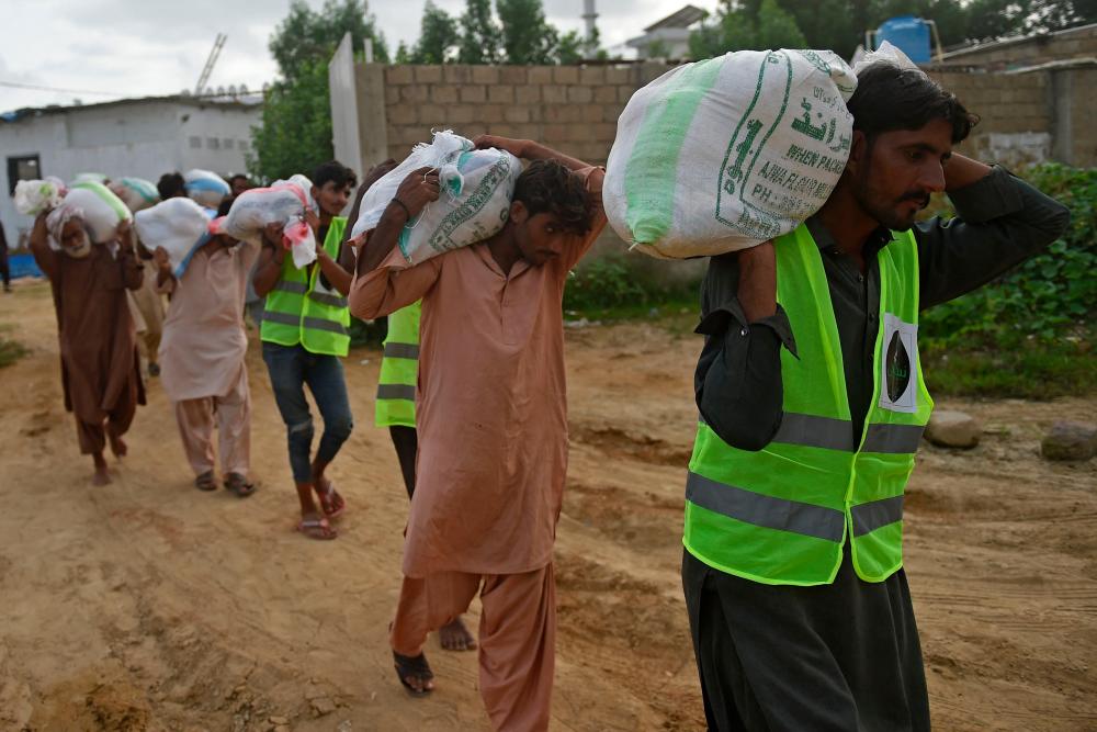 Volunteers carry relief food bags to load on a truck for flood affected people in Karachi on August 28, 2022. AFPPIX