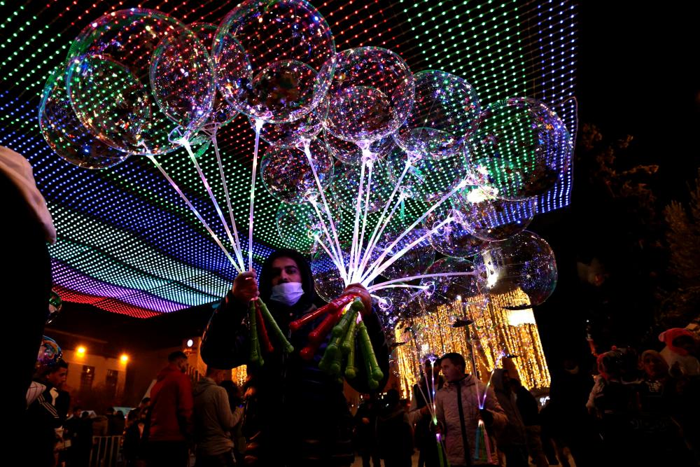 Vendors sell balloons to visitors in Manger Square on Christmas eve outside the Church of the Nativity, revered as the site of Jesus Christ's birth, in the biblical city of Bethlehem in the Israeli occupied West Bank on December 24, 2021. AFPPIX