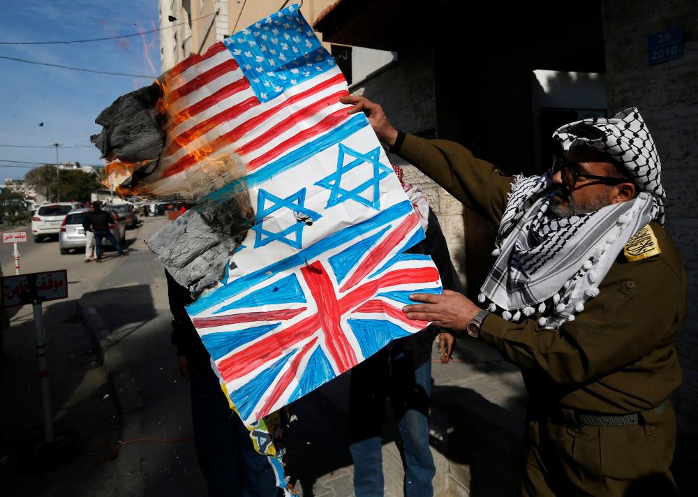 A Palestinian demonstrator, dressed up like the late leader Yasser Arafat, buts along with other protesters drawings representing the flags of Israel (C), Britain and the United States during a protest against his Middle East peace plan, on January 27, 2020 in Gaza City. - AFP
