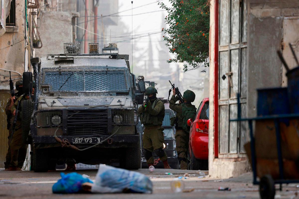 An Israeli soldier aims his weapon during a raid at the Balata refugee camp east of Nablus city in the occupied West Bank on August 11, 2025. - Jaafar ASHTIYEH / AFP