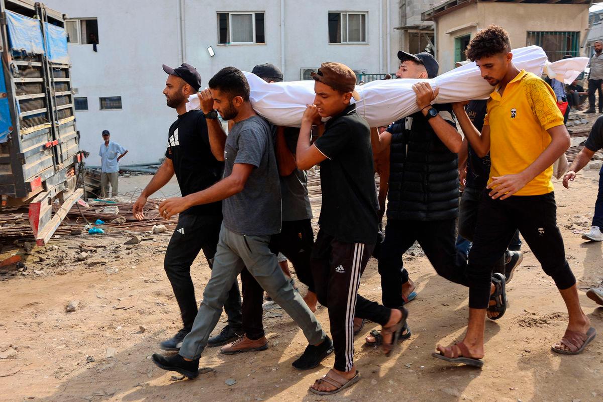 Palestinians carry the shrouded body of a loved one killed the previous day while seeking aid near Zikim, west of Beit Lahia, in the northern Gaza Strip, at Al-Shifa hospital in Gaza City on August 10, 2025- AFP