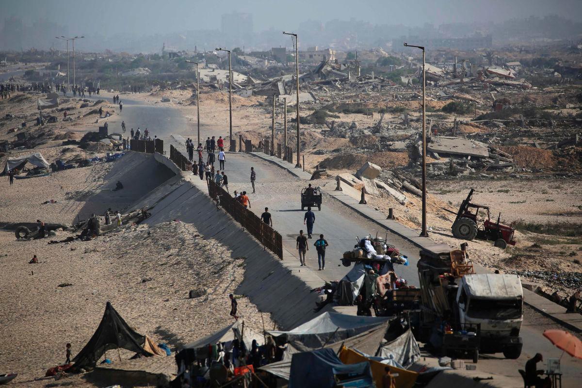 Palestinians walk on a coastal path northwest of Nuseirat refugee camp as they are displaced southward following an Israeli announcement of closing Al-Rashid road towards the north of the besieged Gaza Strip on October 4, 2025. (Photo by Eyad BABA / AFP)