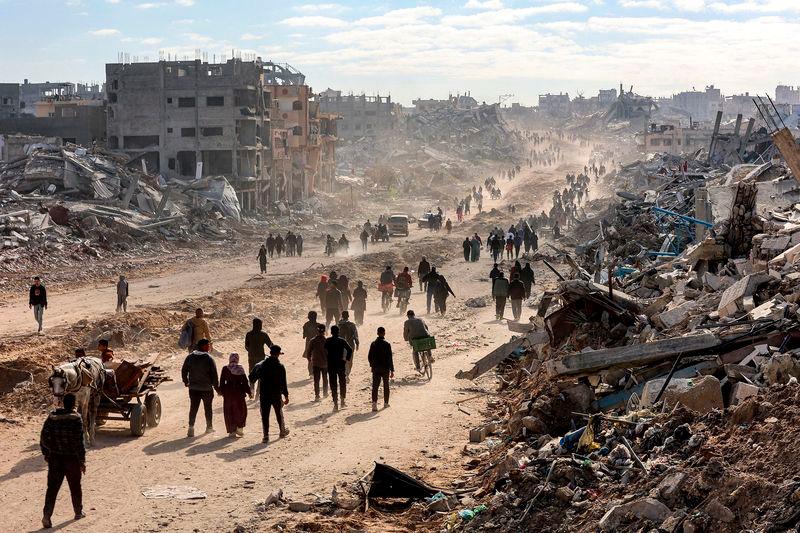 People walk past the rubble of collapsed buildings along Saftawi street in Jabalia in the northern Gaza Strip - REUTERSpix