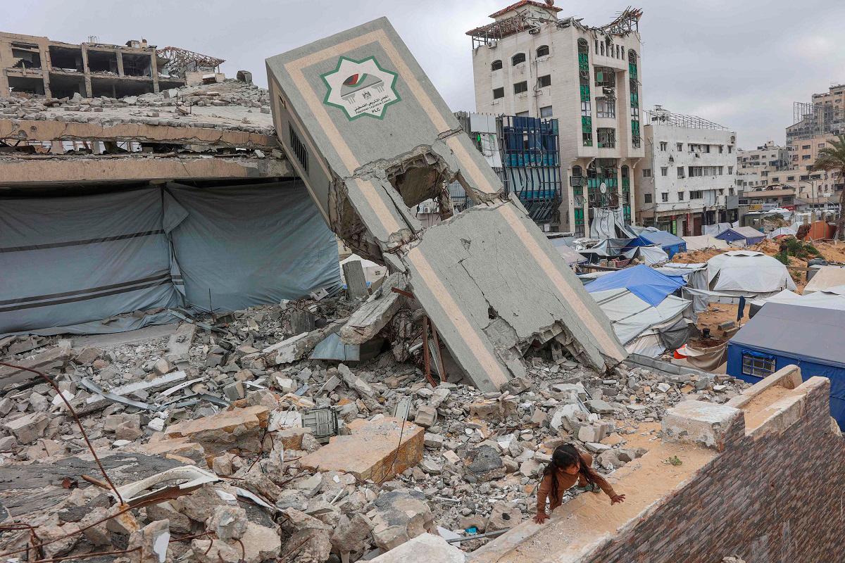 A Palestinian girl plays on the rubble of a Palestinian Authority's Legislative Council building near a makeshift displacement camp set up amid building rubble in Gaza City on May 12, 2025. Israeli Prime Minister Benjamin Netanyahu said on May 12 that the release of a US-Israeli hostage announced by Hamas would not lead to a ceasefire in the Gaza Strip or the release of Palestinian detainees. - Omar AL-QATTAA / AFP