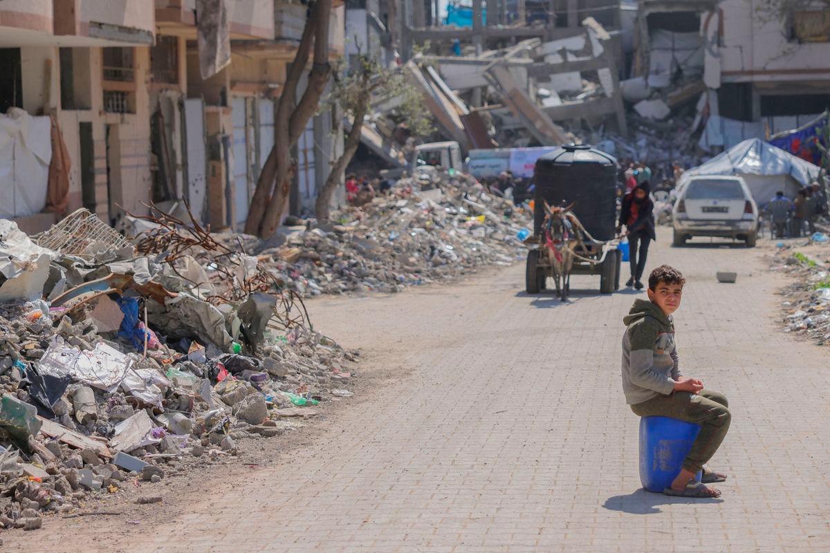 A Palestinian boy sits on a plastic container after re-supplying with water at a distribution point at a displacement camp west of Jabalia city in the northern Gaza Strip - AFPpix