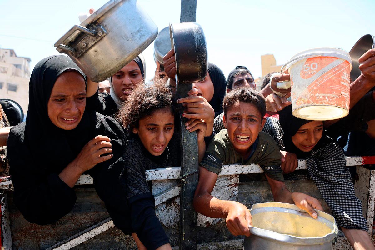 Palestinians receive lentil soup at a food distribution point in Gaza City on August 2, 2025. The World Health Organisation warned on July 27 that malnutrition was reaching “alarming levels” in Gaza. - Omar AL-QATTAA / AFP