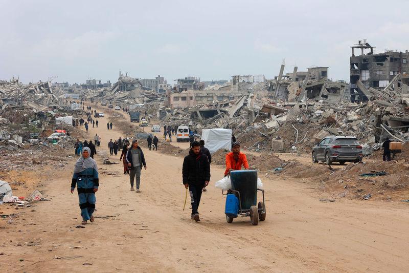 Palestinians walk past collapsed buildings along Saftawi street in Jabalia in the northern Gaza Strip - AFPpix