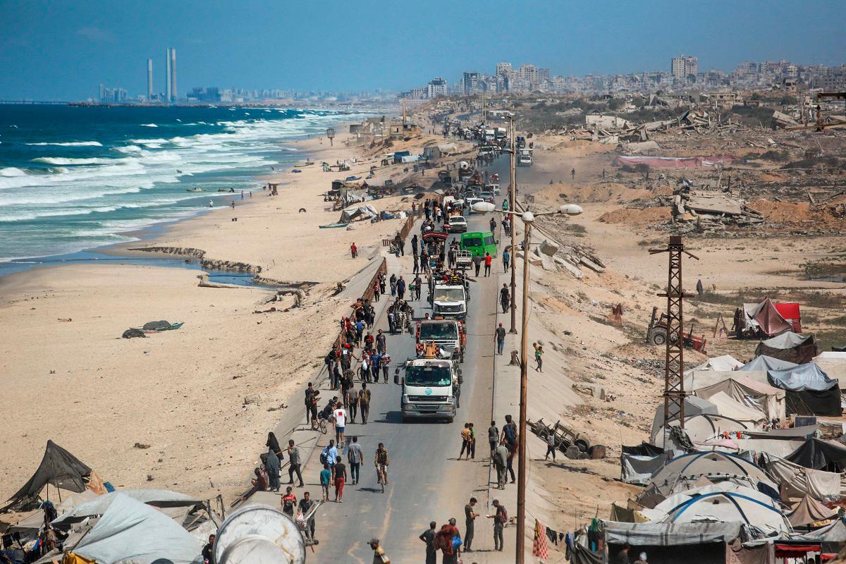 Palestinians carrying belongings arrive on a coastal path northwest of Nuseirat refugee camp as they are displaced southward from Wadi Gaza following an Israeli announcement of closing Al-Rashid road towards the north of the besieged Gaza Strip on October 1, 2025. - Bashar TALEB / AFP