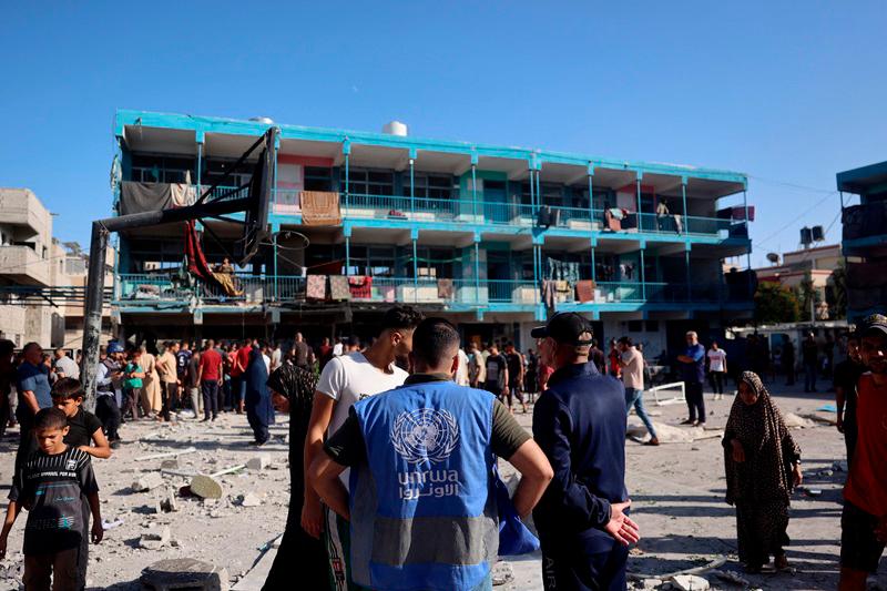 A member of the United Nations Relief and Works Agency for Palestine Refugees (UNRWA) checks the courtyard of a school after an Israeli air strike hit the site, in Nuseirat in the central Gaza Strip on September 11, 2024, amid the ongoing war in the Palestinian territory between Israel and Hamas. An Israeli air strike on September 11 hit a central Gaza school, with the Hamas-run territory's civil defence agency reporting 10 killed in the facility turned displacement shelter and the military saying it had targeted militants. - Eyad BABA / AFP