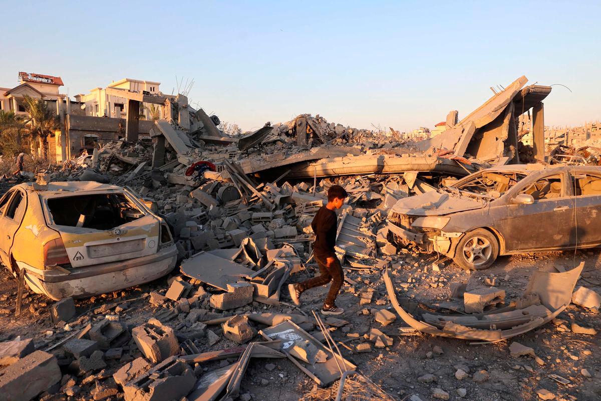 A Palestinian youth walks past the destruction of homes and buildings in the Al-Bureij camp in the central Gaza Strip after an Israeli strike, on June 27, 2025, amid the ongoing conflict between Israel and the Palestinian Hamas militant group. (Photo by Eyad BABA / AFP)