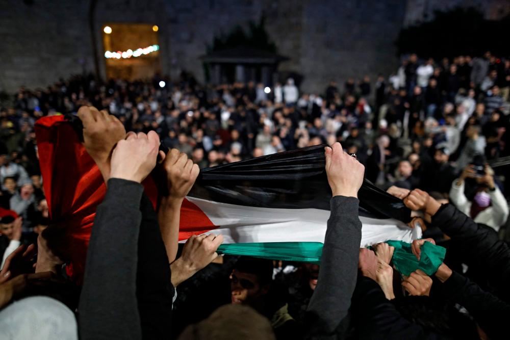 Palestinian protesters wave the national flag outside the Damascus Gate in Jerusalem's Old City on April 26, 2021. –AFP