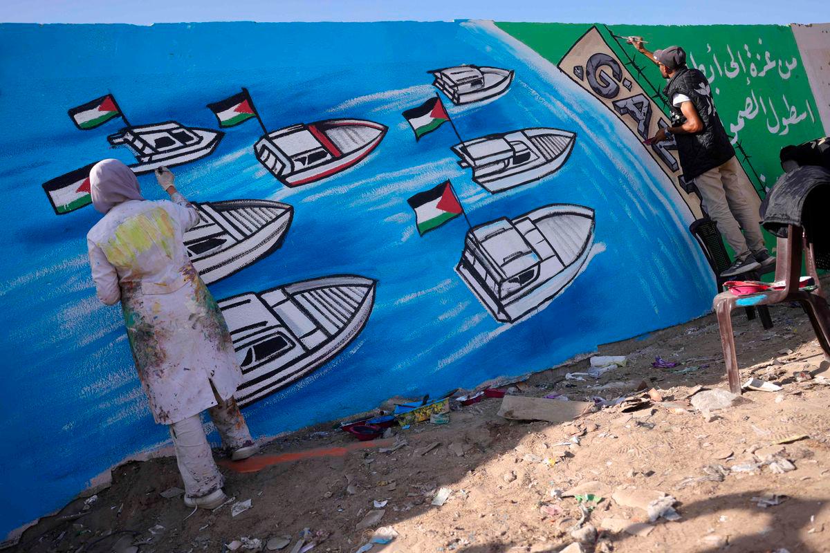 Palestinian artists work on a mural painting representing the Global Sumud Flotilla bound for Gaza, as a gift of appreciation for the activists who were aboard, in Deir el-Balah in the central Gaza Strip on October 3, 2025. (Photo by Bashar TALEB / AFP)