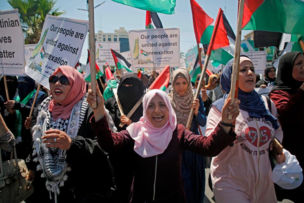 Palestinian women chant and lift placards and national flags during a demonstration against Israel's West Bank annexation plans in Gaza City on July 1, 2020. Expectations of a major Israeli announcement on controversial annexations in the occupied West Bank dimmed, as global criticism of the project mounted and Palestinian protesters began gathering in Gaza. — AFP