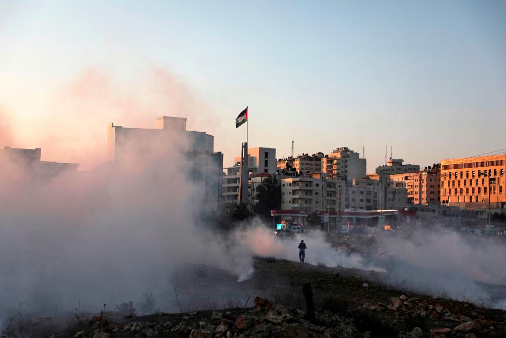 Smoke billows during clashes between Palestinian protesters and Israeli forces in the Israeli-occupied West Bank, on Nov 11. — AFP
