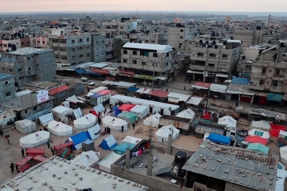 Displaced Palestinians stand outside their tents in Rafah in the southern Gaza Strip on February 14, 2024, amid the continuing battles between Israel and the Palestinian Hamas militant group. - AFPPIX