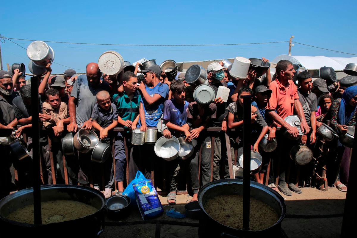 Palestinians wait to receive food portions from a charity kitchen in Khan Yunis in the southern Gaza Strip on August 27, 2025. (Photo by AFP)
