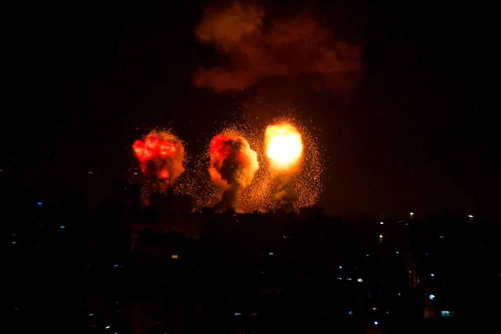 A ball of fire and a plume of smoke rise above buildings in south of City Strip as Israeli warplanes target the Palestinian enclave, early on, on December 4, 2022/AFPPix